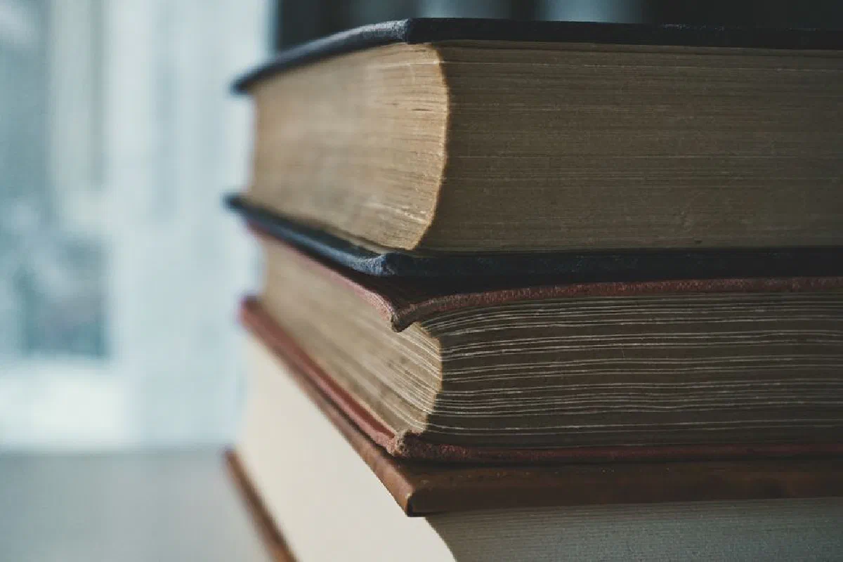 A close-up view of a stack of vintage books with worn pages and covers in soft lighting.