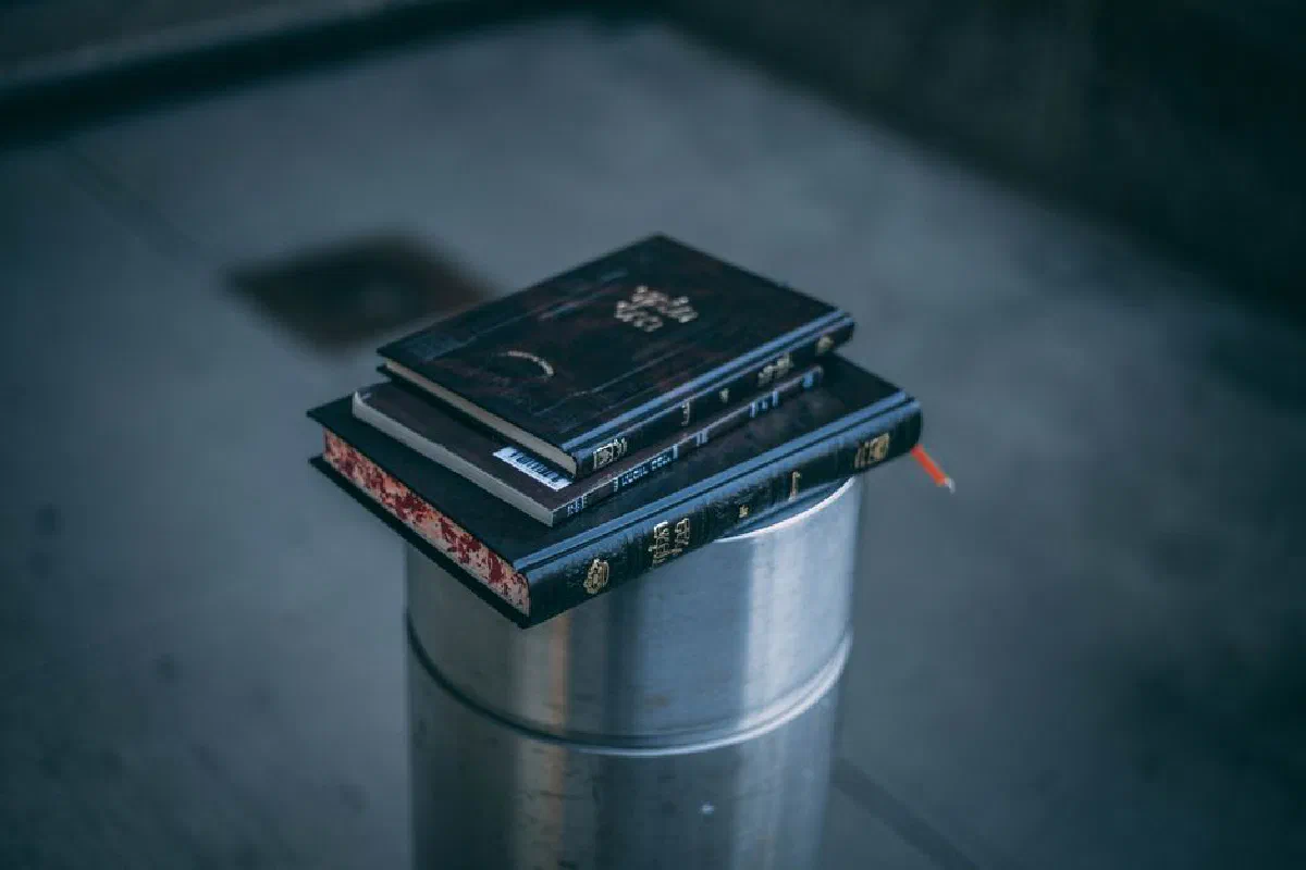 A close-up photo of a stack of books resting on a steel container indoors.