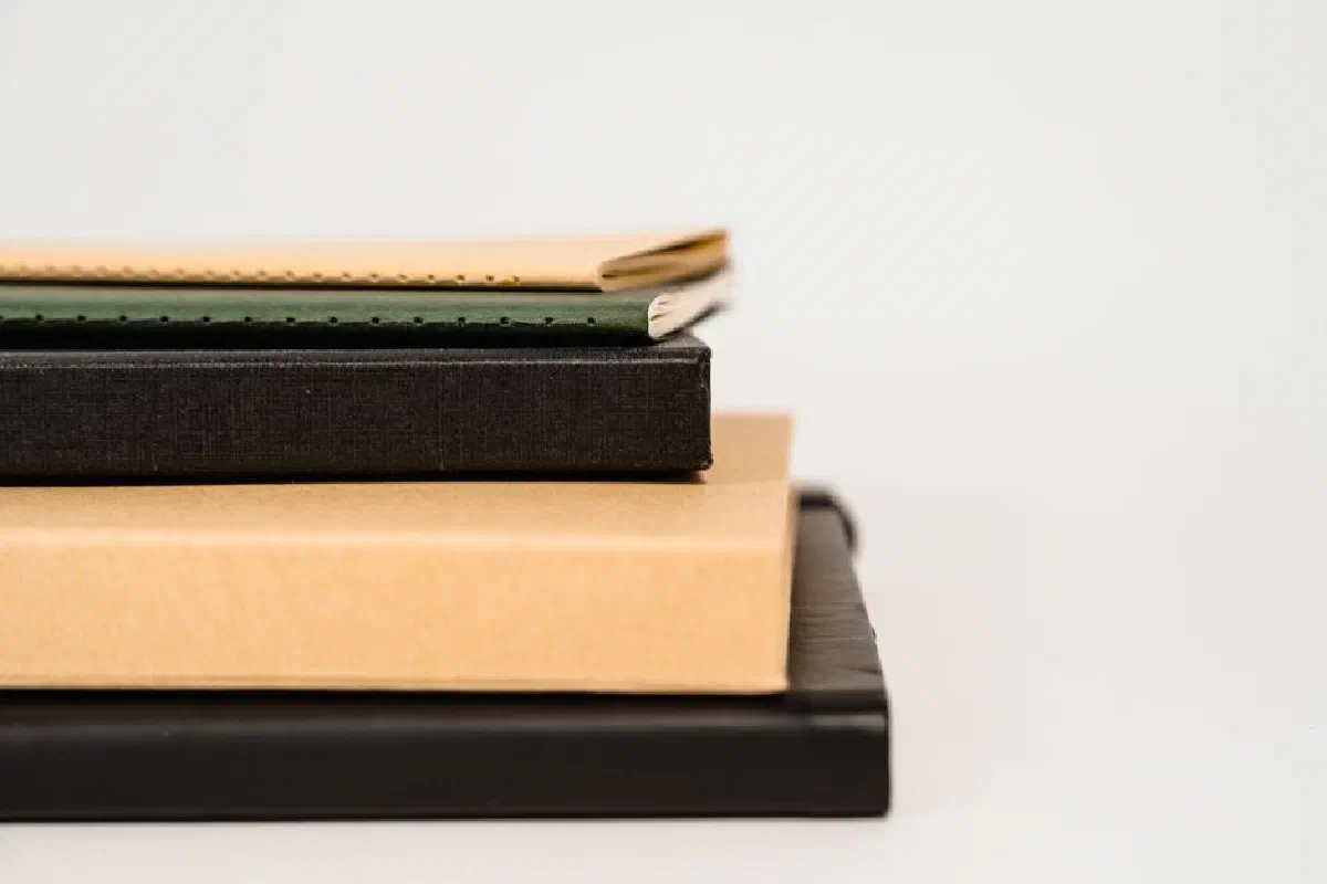 Close-up of stacked notebooks on a light background, highlighting texture and simplicity.