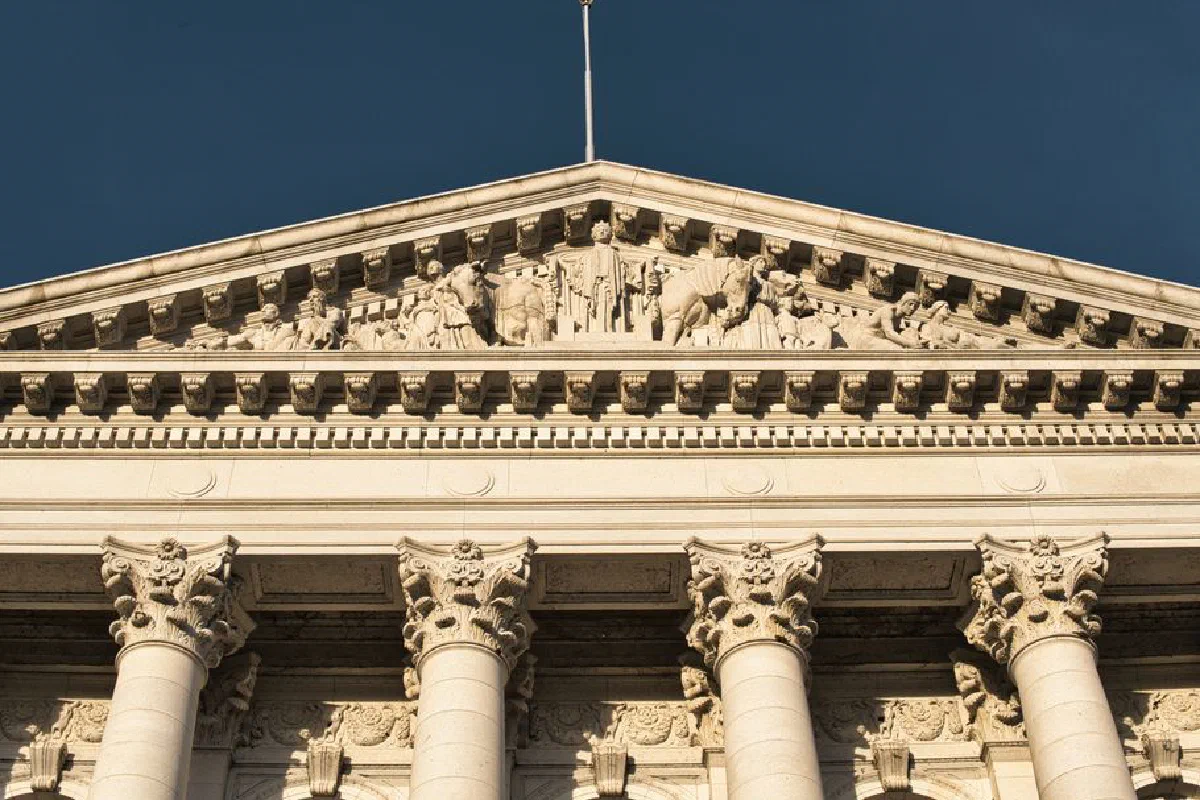 Close-up of neoclassical architecture in Madison, Wisconsin, showcasing ornate columns and pediment under a clear blue sky.