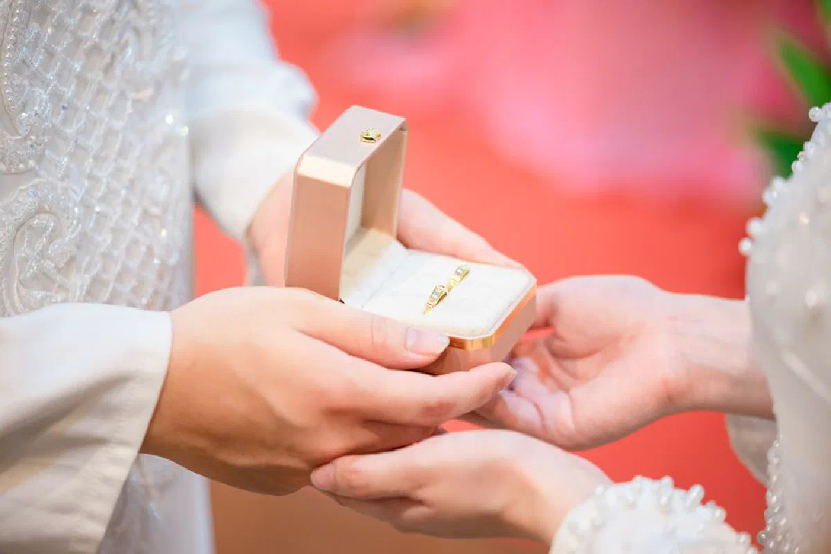 Close-up of hands exchanging wedding rings during a ceremony.