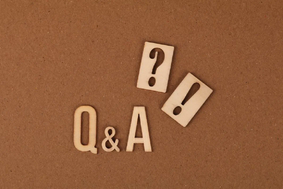 Wooden cutouts of Q&A with question and exclamation marks on a brown backdrop.
