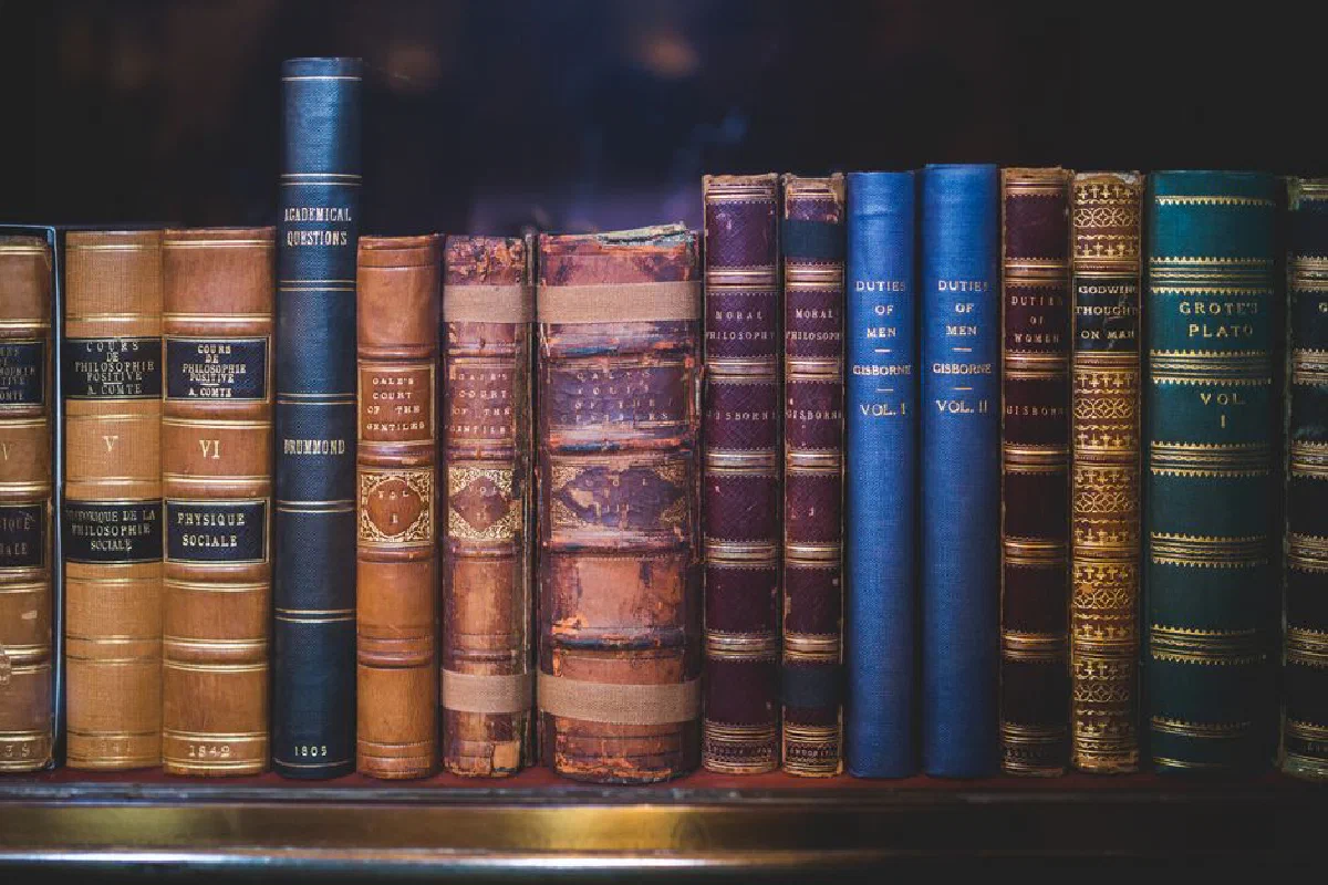 A collection of classic, leather-bound books neatly arranged on a wooden bookshelf.