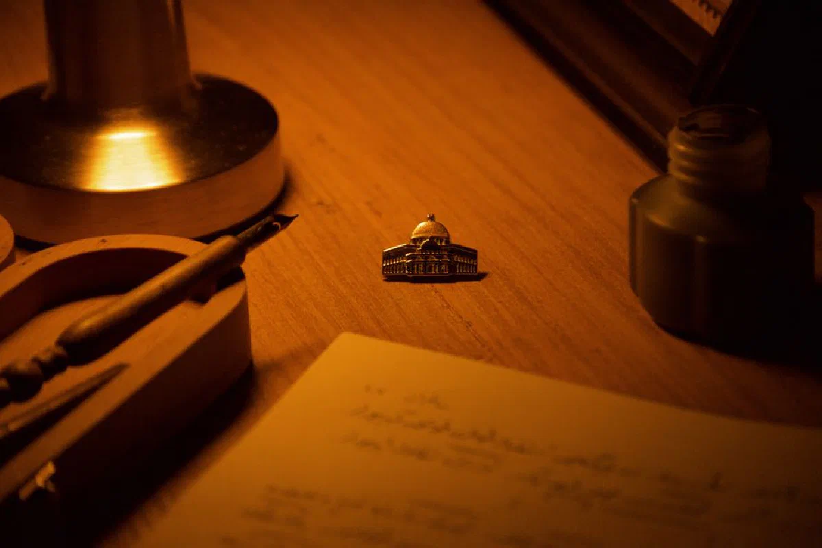 Warm-toned desk scene with lamp, ink pot, and decorative object.