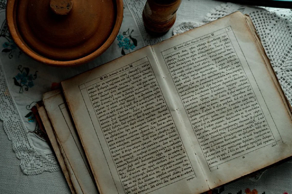 Ancient manuscript open on table with pottery, creating a nostalgic vintage atmosphere.