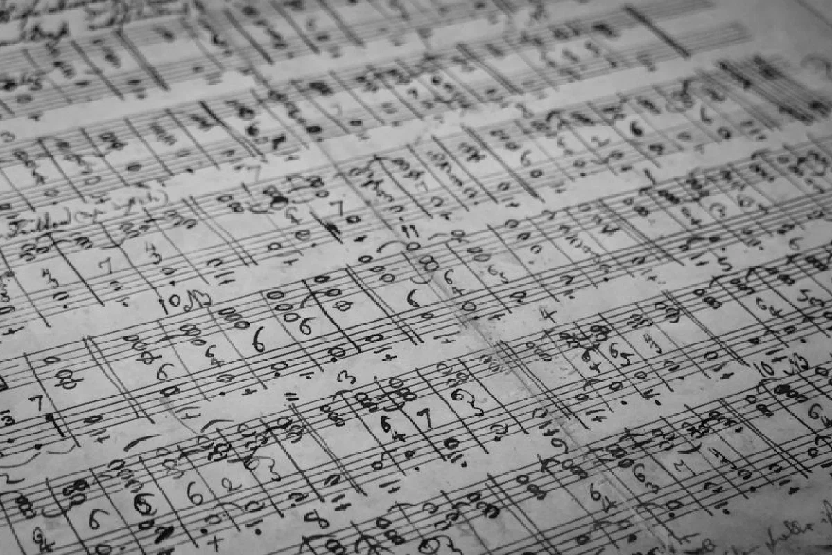 Detailed black and white photo of handwritten music sheets with notes and symbols.