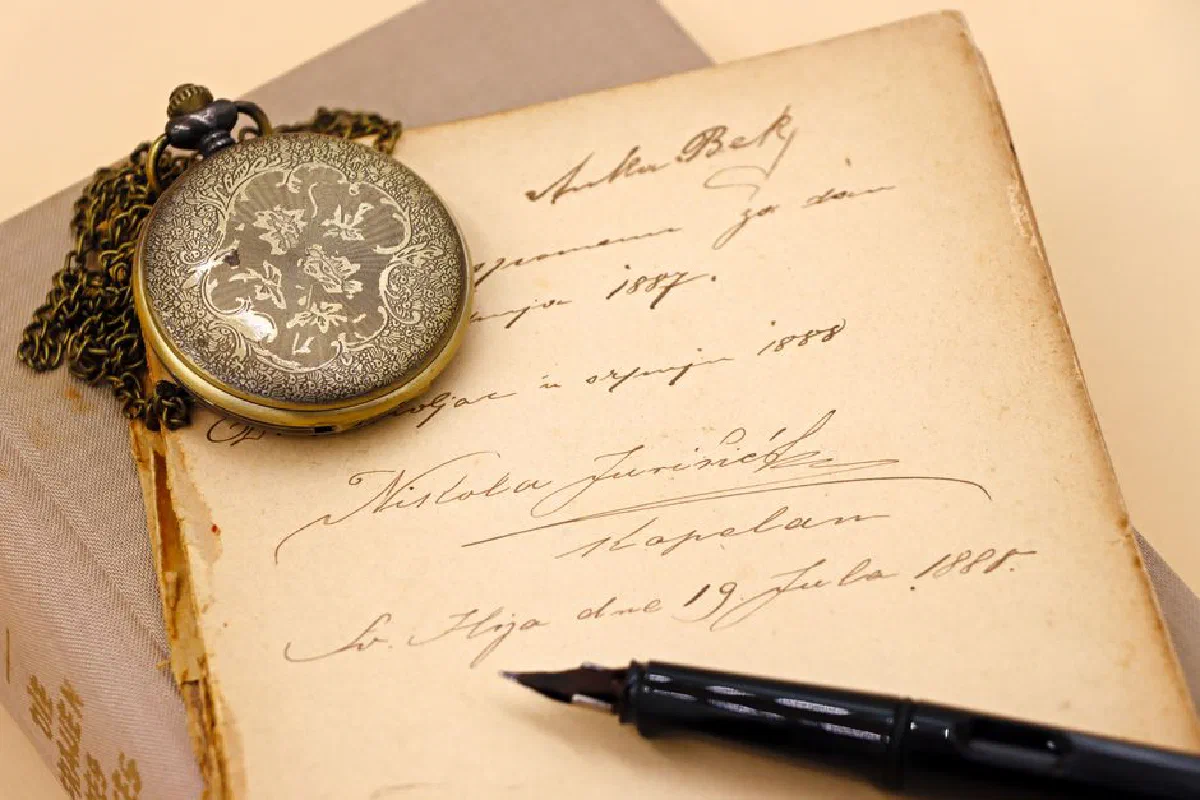 An antique pocket watch rests on an old journal featuring elegant handwriting, evoking a sense of history and heritage.