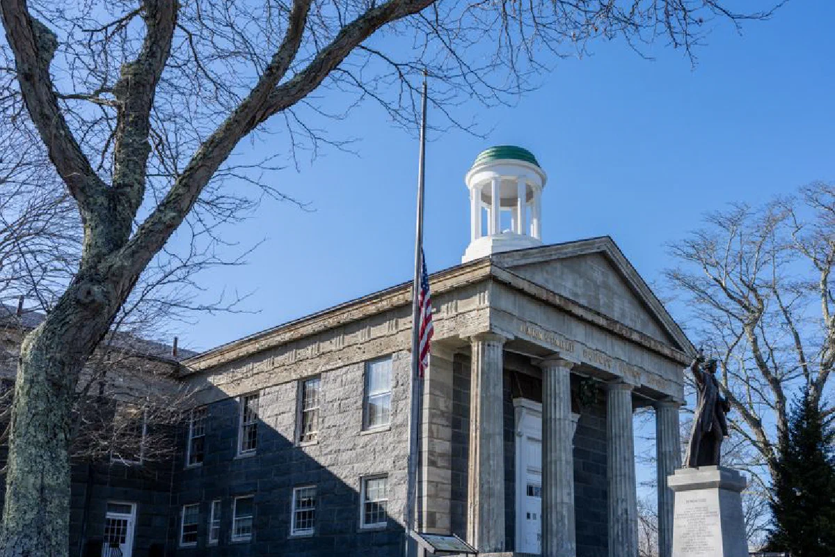 Front view of the historic Barnstable County Courthouse with a prominent statue and flag.