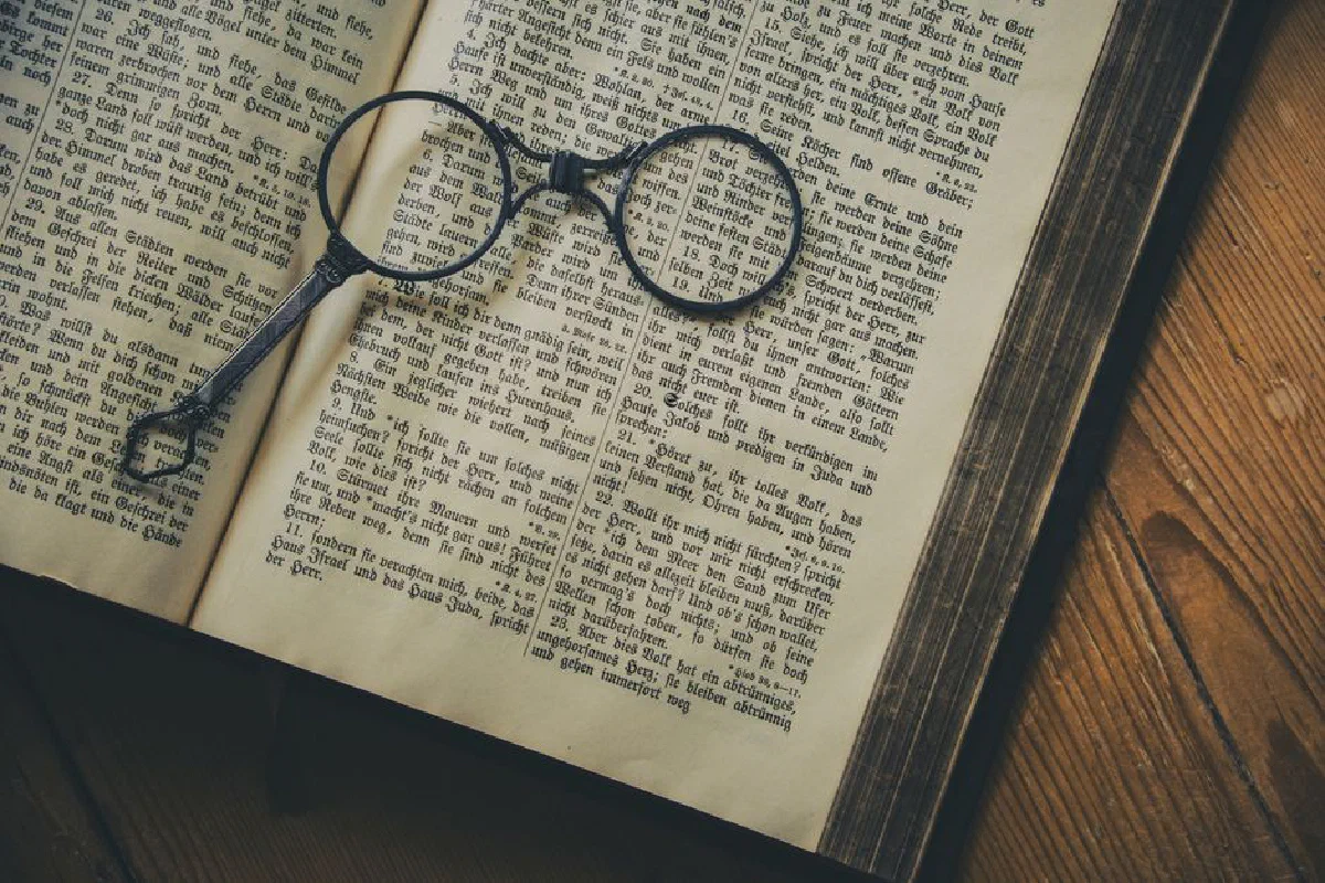 A vintage book with old-fashioned spectacles resting on its pages, symbolizing knowledge and history.