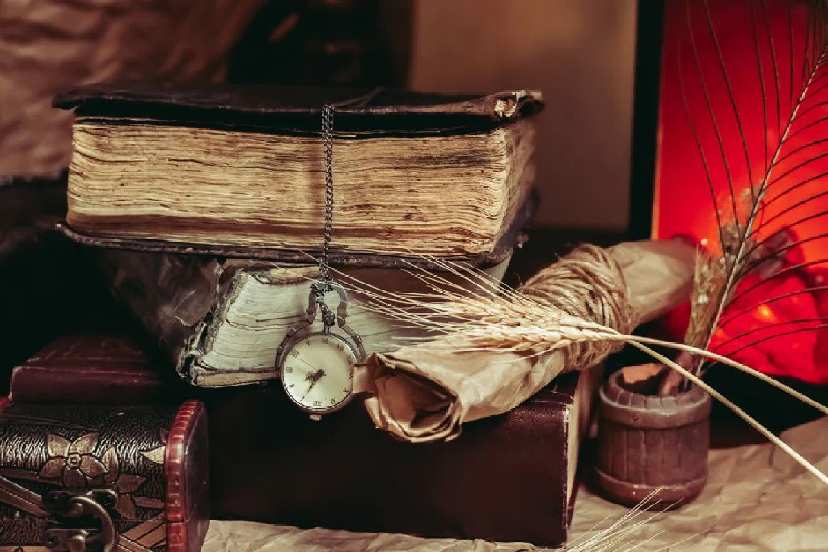 A vintage still life arrangement with old books, a pocket watch, and a rustic setting.