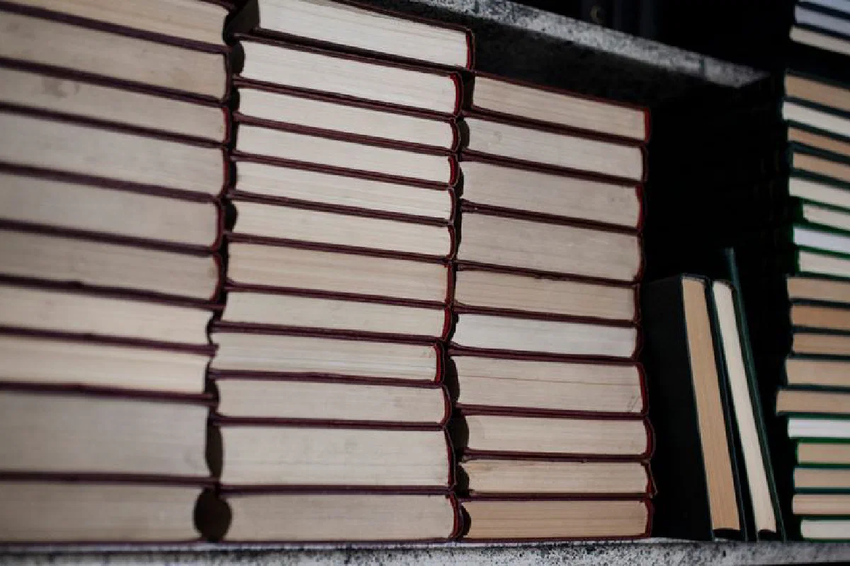 A neat stack of hardcover books on a bookshelf, showing organized bindings.