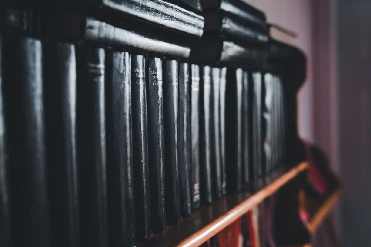Close-up of black hardcover books neatly arranged on a wooden shelf.