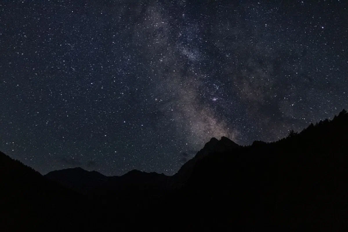 Capture of the Milky Way galaxy in a clear night sky over a mountain silhouette.