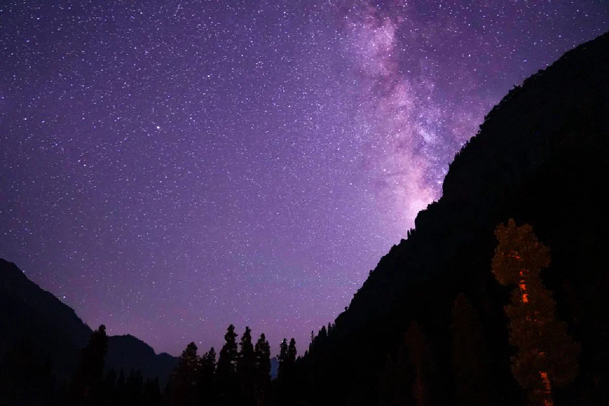 Silhouetted mountains under a stunning starry night sky, showcasing the Milky Way in vivid detail.