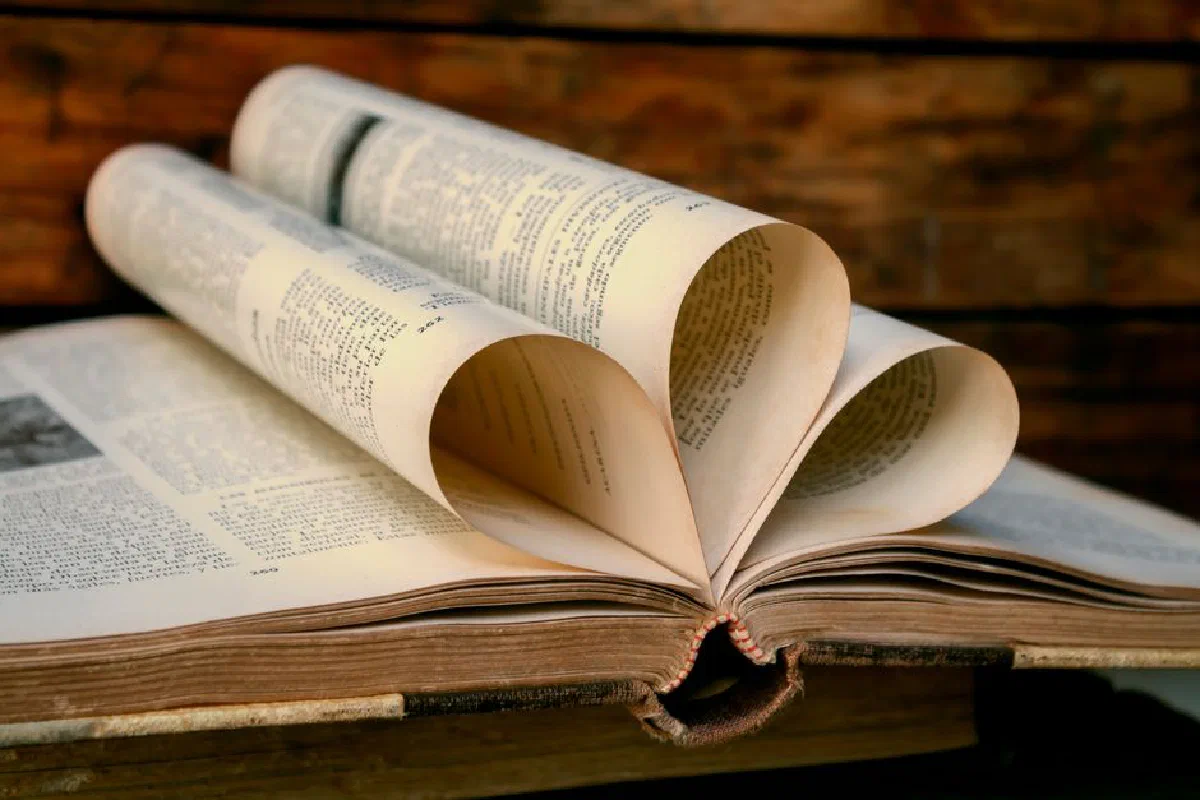 A vintage book with heart-shaped pages against a wooden background, symbolizing love for reading.