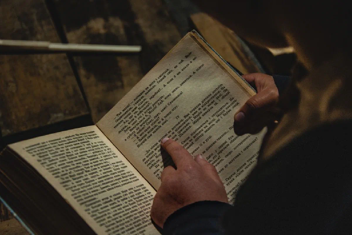 Hands reading an open book, highlighting the intimate act of reading and learning.