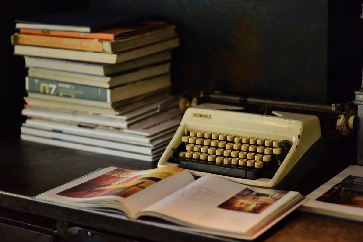 A nostalgic scene with an old typewriter and a stack of books on a wooden desk.