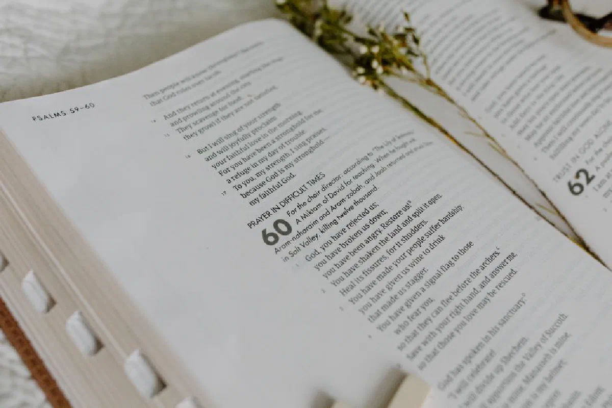 Close-up of an open Bible showing Psalm 60 with dried flowers.