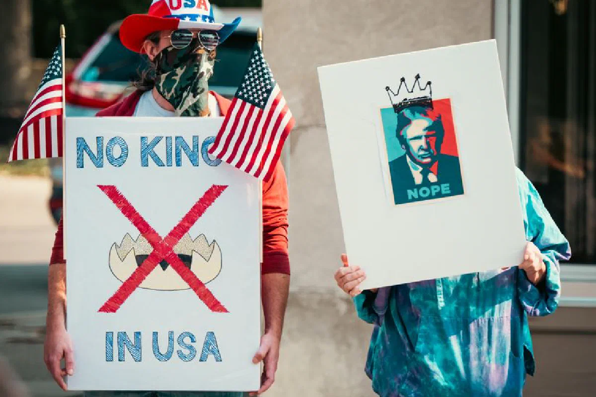 Two protesters displaying political signs during a demonstration with US flags.