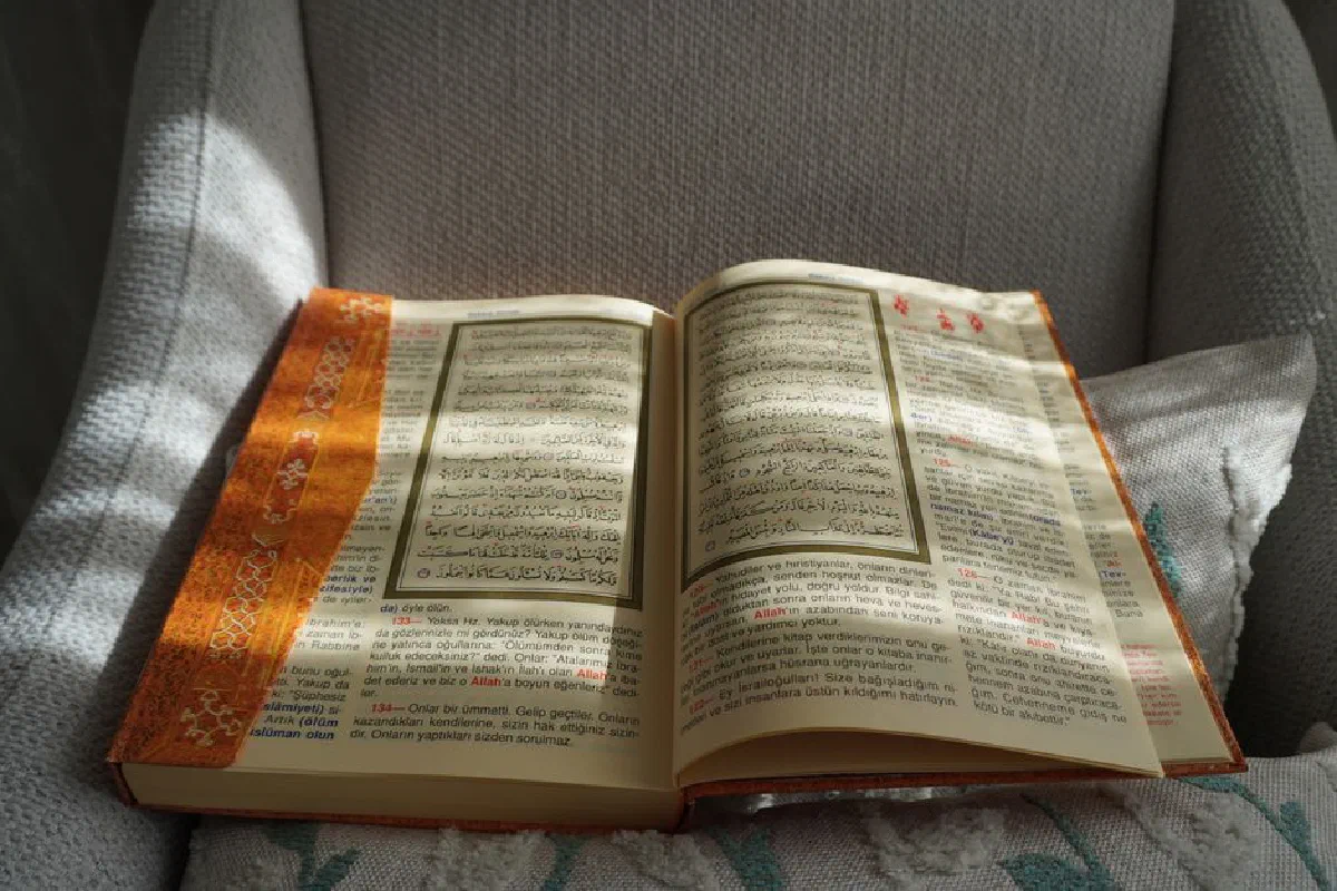 An open Quran with Arabic and Turkish text on a sunlit chair, creating a serene and spiritual atmosphere.