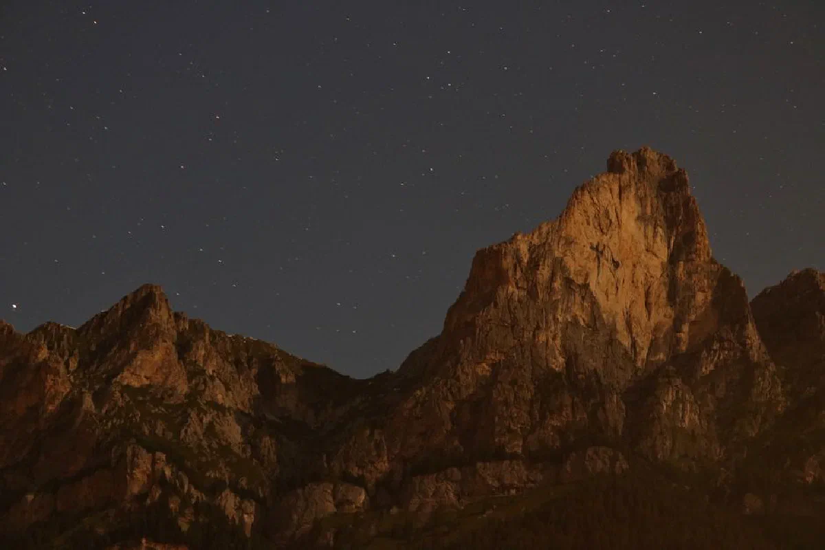 A scenic view of rugged rock mountains beneath a starry night sky.