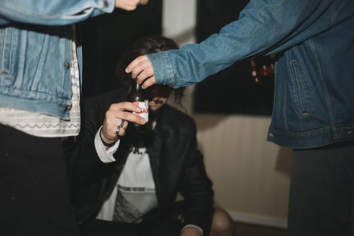 A close-up shot of friends socializing, sharing drinks, and wearing denim jackets indoors.