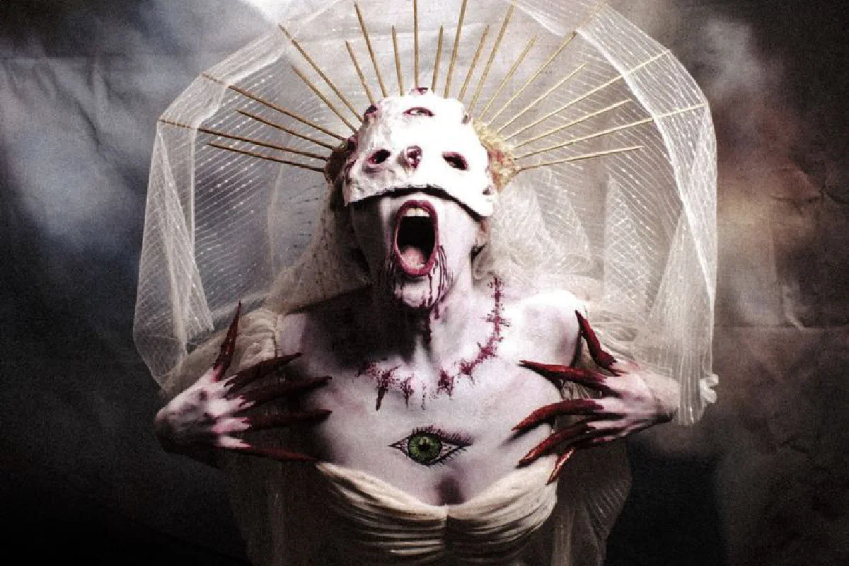 Gothic woman with a haunting costume, veil, and painted mask in an artistic horror portrait.