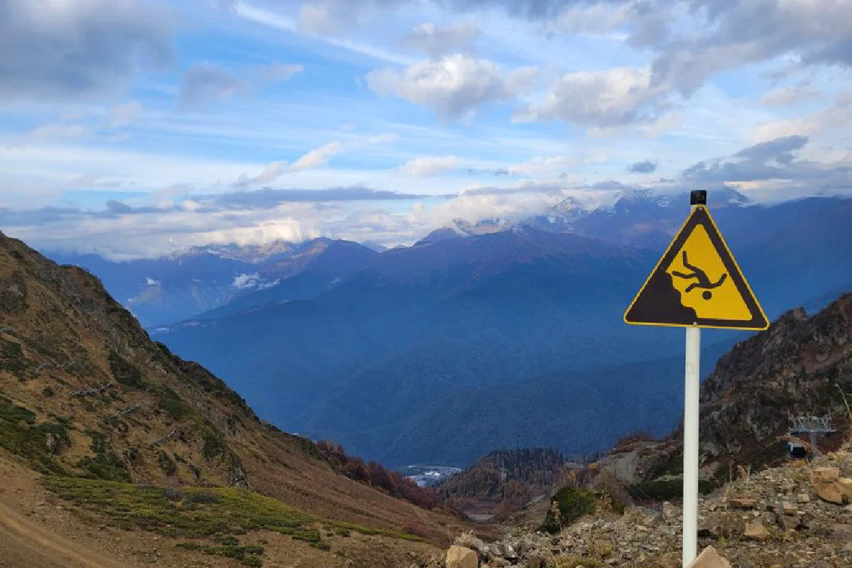 Breathtaking view of mountains with a warning sign indicating cliff danger. Ideal for adventure and travel themes.