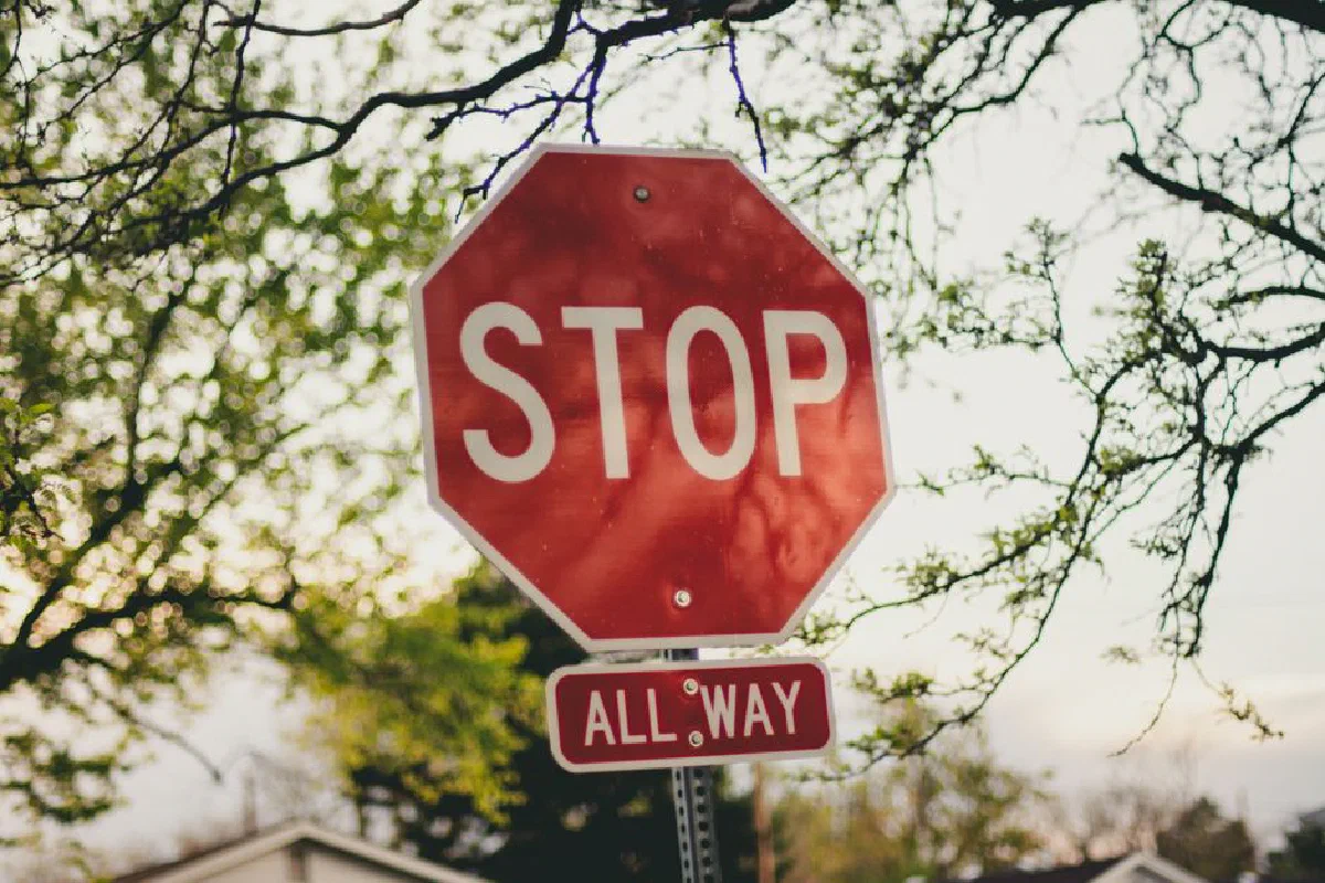 A clear red stop sign with 'All Way' below it in a sunny suburban setting.