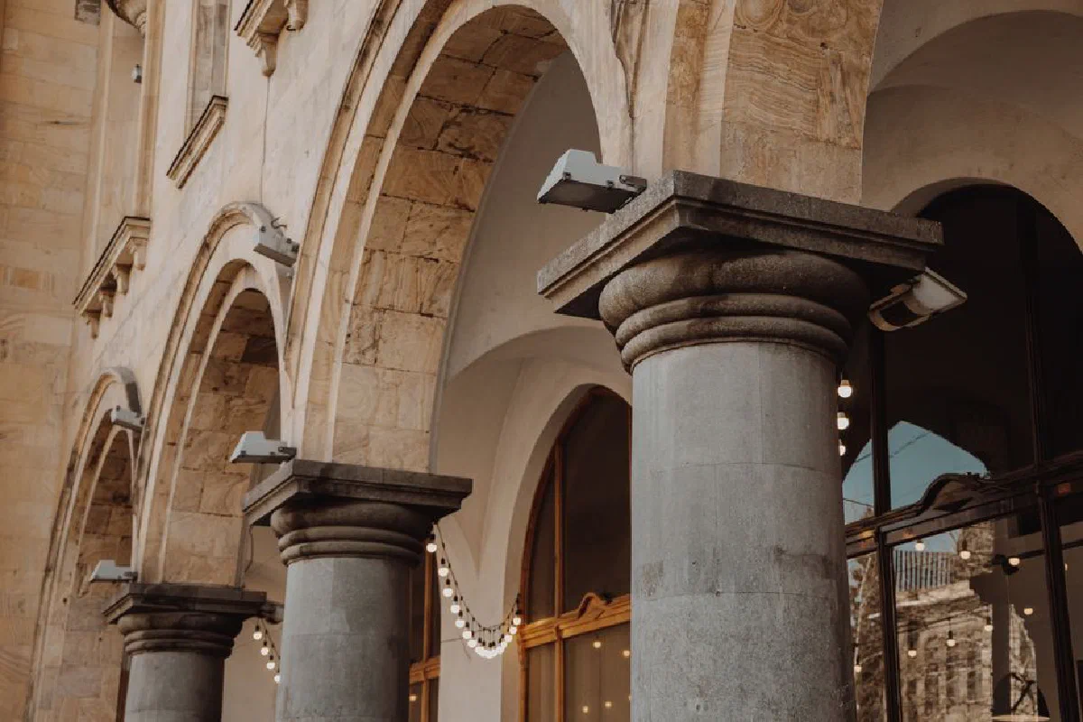 Classic architectural arches and columns of a building exterior with stone elements and lighting.