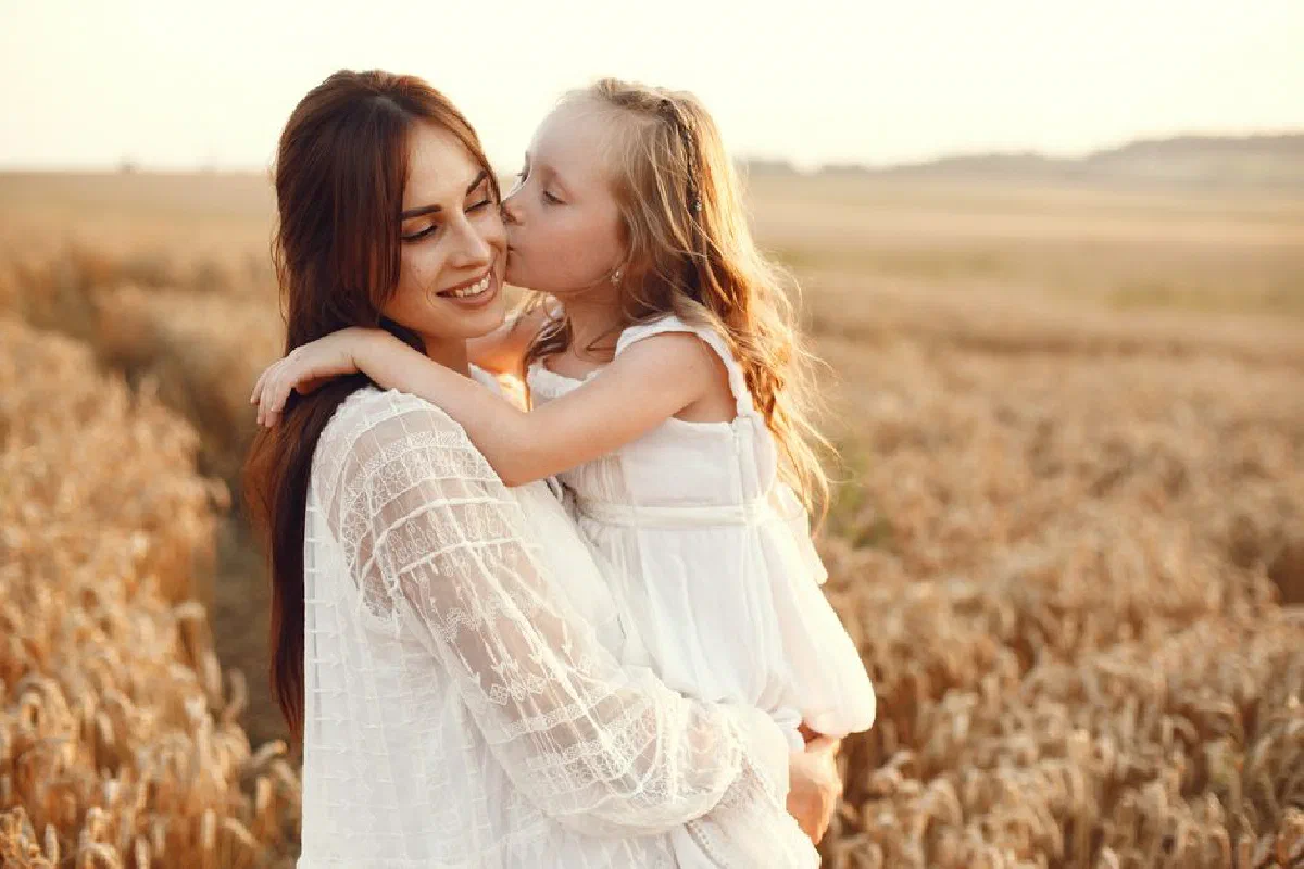 A loving moment between mother and daughter in a sunlit wheat field.