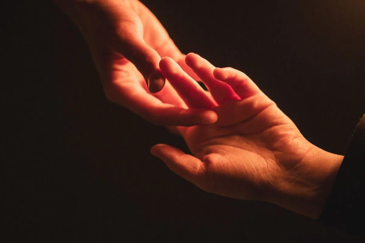 Close-up of two hands reaching towards each other, creating an intimate connection.