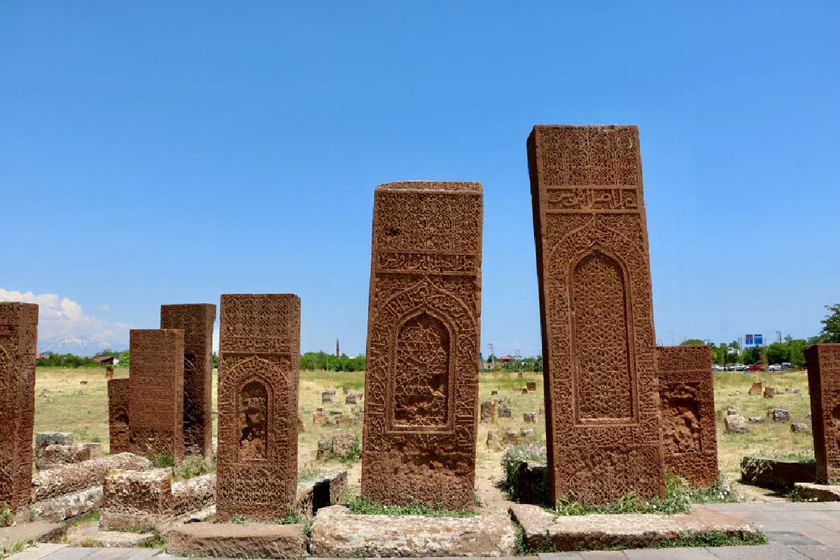 Historic Armenian tombstones with intricate carvings beneath a clear blue sky, showcasing ancient art.