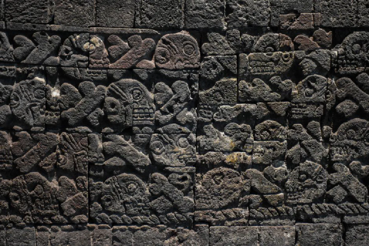 Detailed stone carvings depicting skulls on an ancient wall in Mexico City, representing rich history and art.