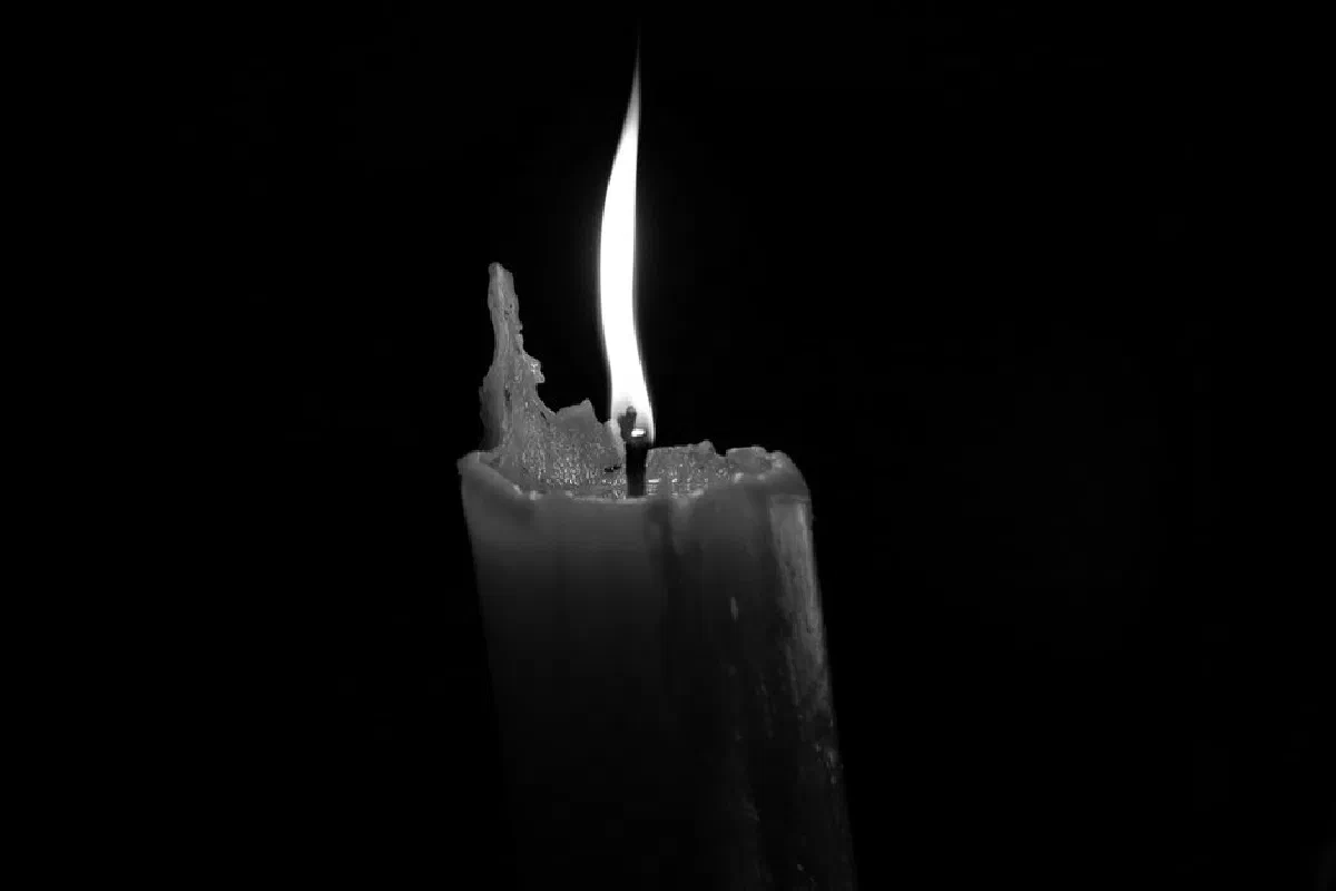 A minimalistic monochrome photo of a burning candle with a bright flame against a dark backdrop.