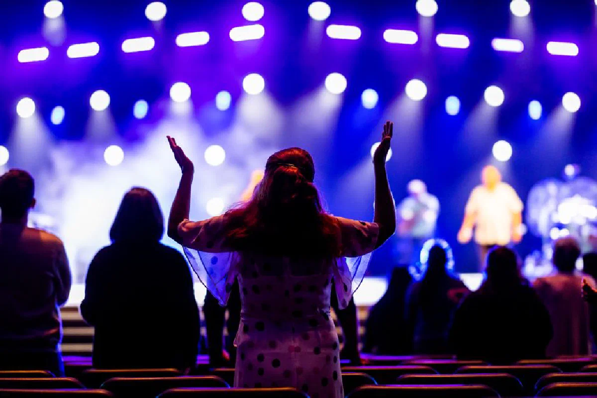 Enthusiastic audience with raised hands enjoying a colorful live concert performance.