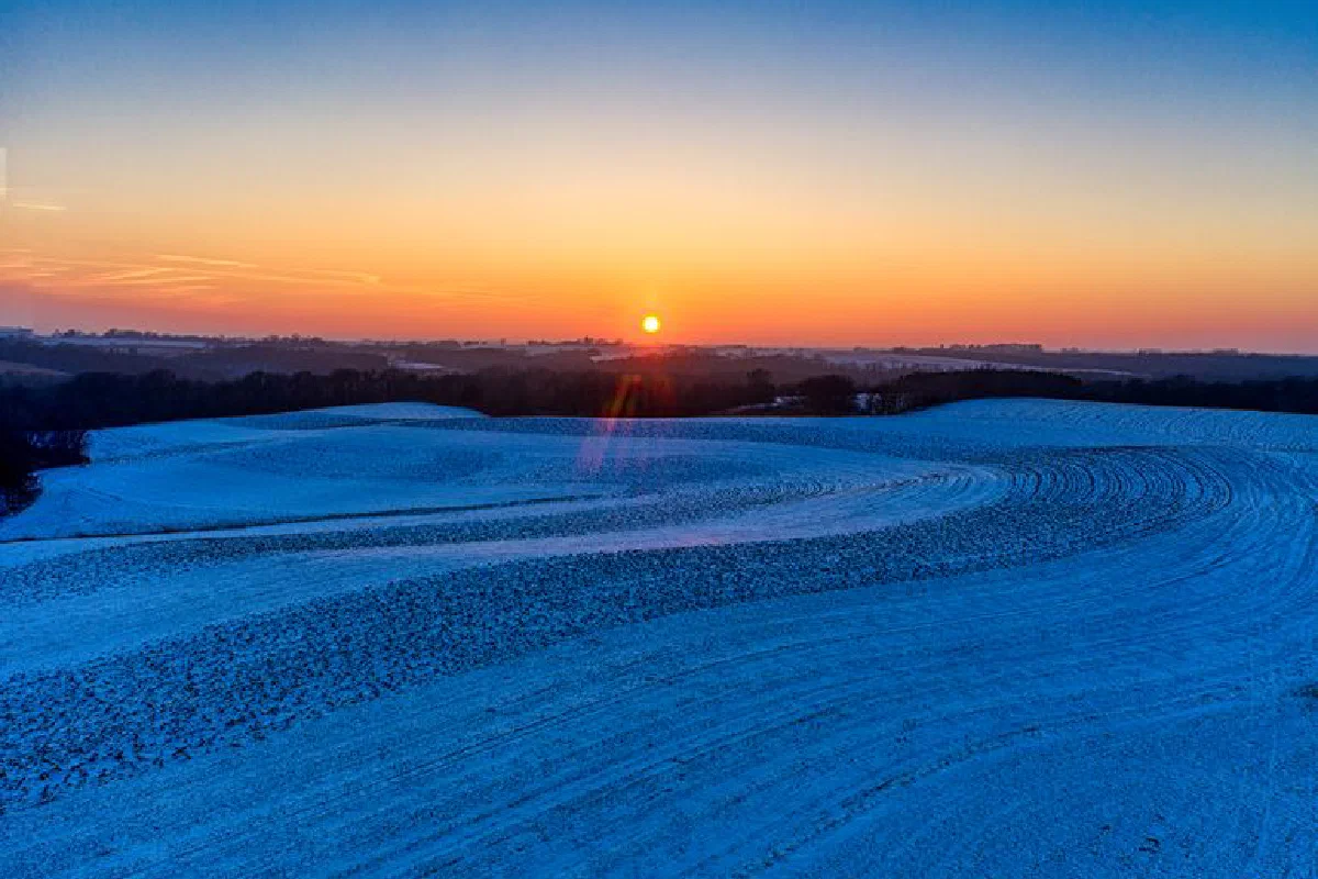 A beautiful winter sunrise over snow-covered fields in Minnesota, USA, showcasing nature's tranquility.