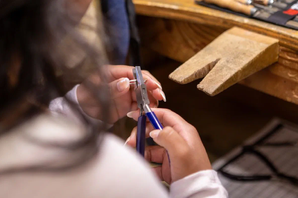 Craftsperson skillfully using pliers in a workshop environment, showcasing detailed craftsmanship.