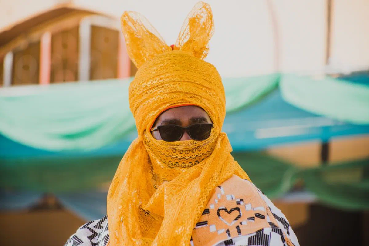 Man in vibrant yellow traditional attire and sunglasses outdoors.