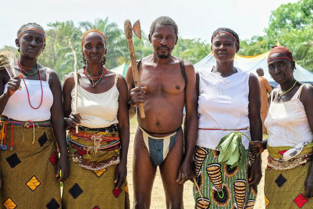 A group of African adults in traditional tribal clothing posing outdoors, showcasing cultural heritage.