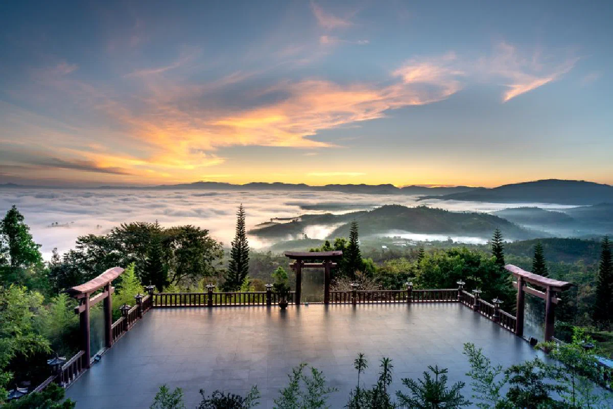 A breathtaking sunrise view from a peaceful oriental courtyard overlooking misty mountains.