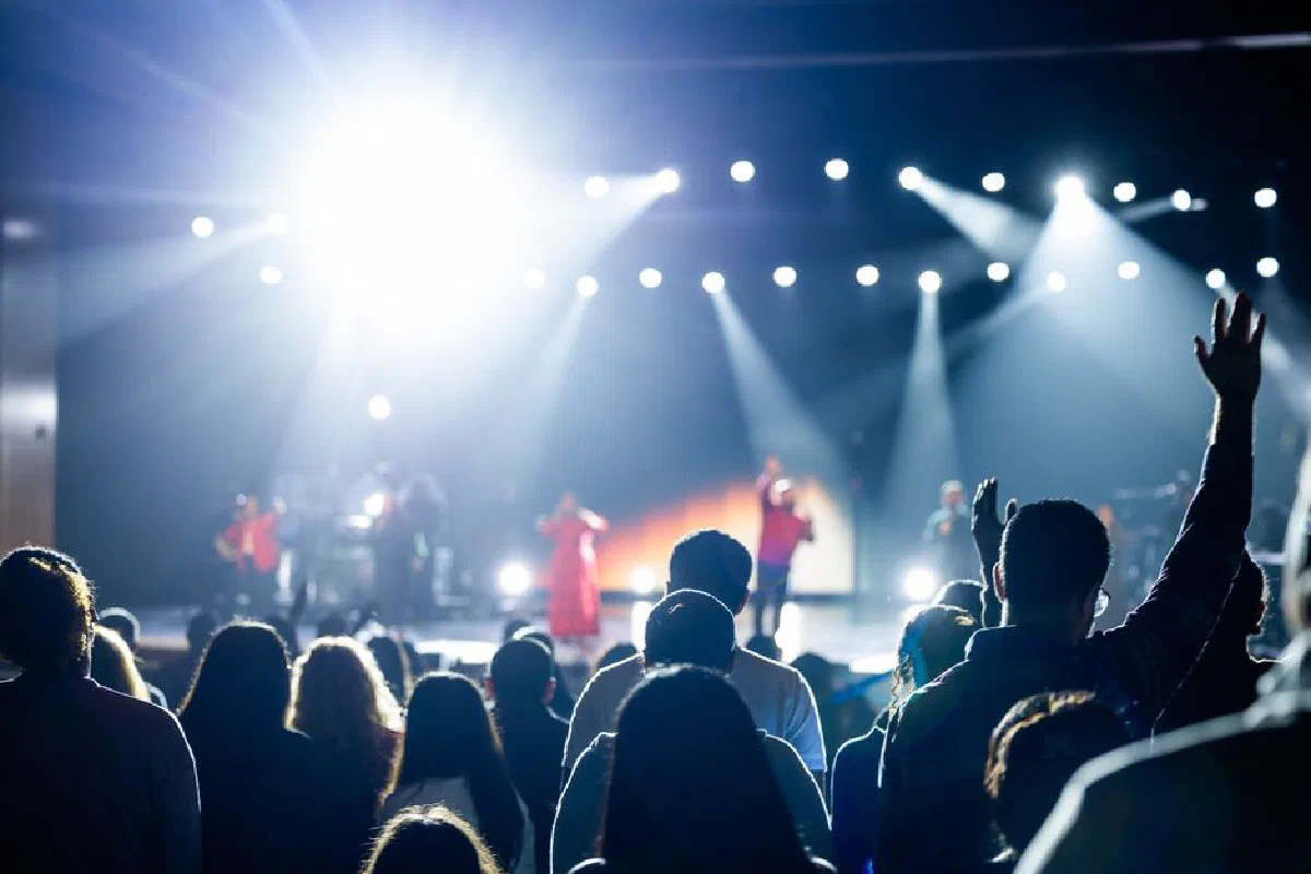 Energetic concert crowd with bright stage lights, capturing a lively atmosphere.