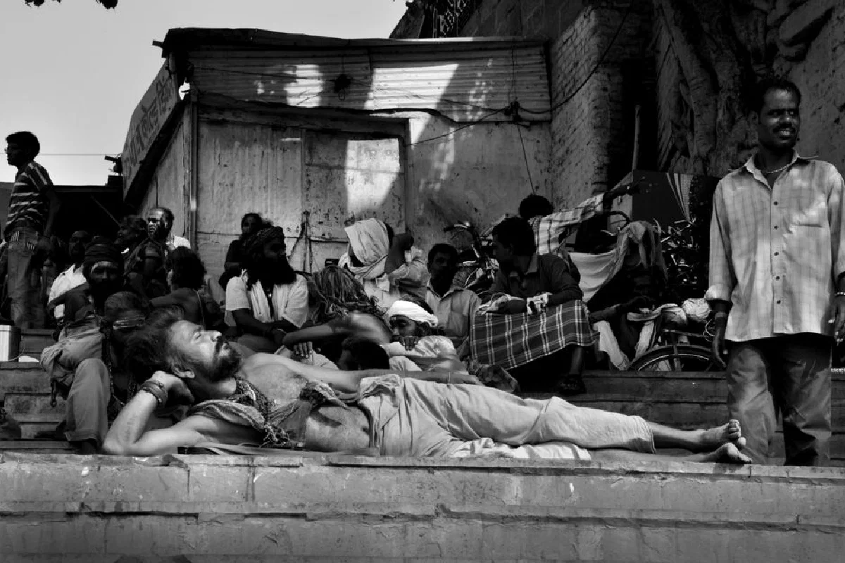 Black and white photo of pilgrims resting at Varanasi's riverbank, capturing the essence of Indian culture.