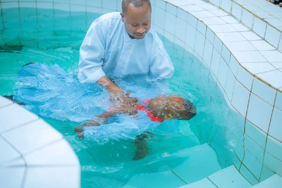 A sacred baptism ceremony taking place in a tiled pool with serene turquoise water.