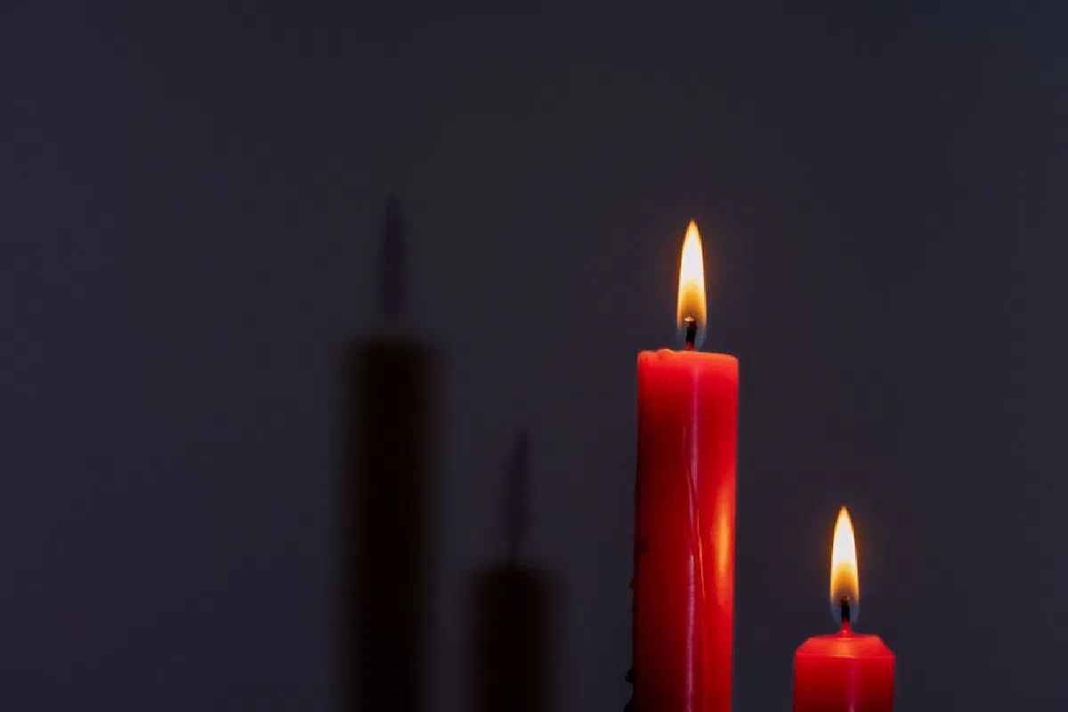 Two red candles illuminate the dark with warm, mysterious shadows.