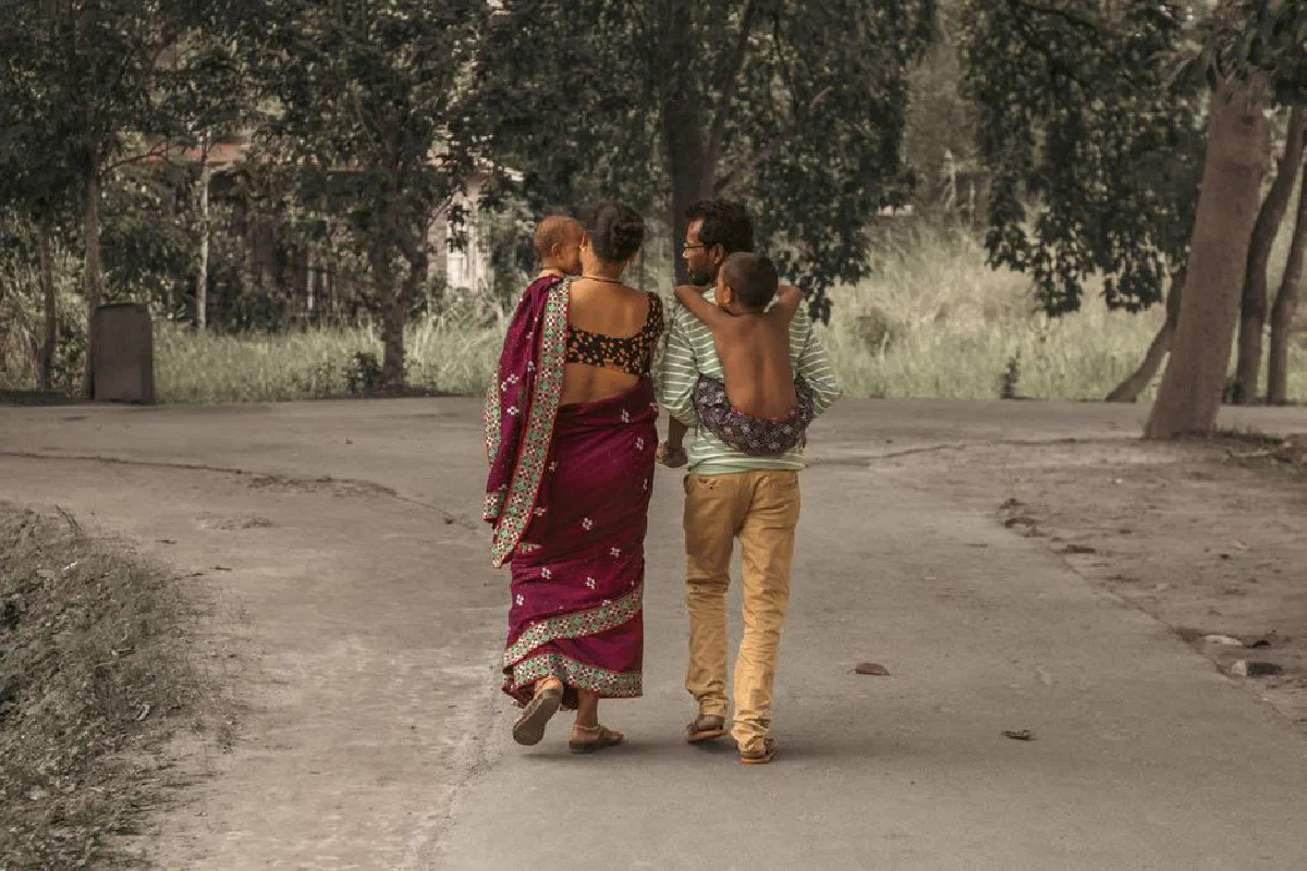 A family enjoys a peaceful walk on a rural road surrounded by lush greenery, fostering connection.