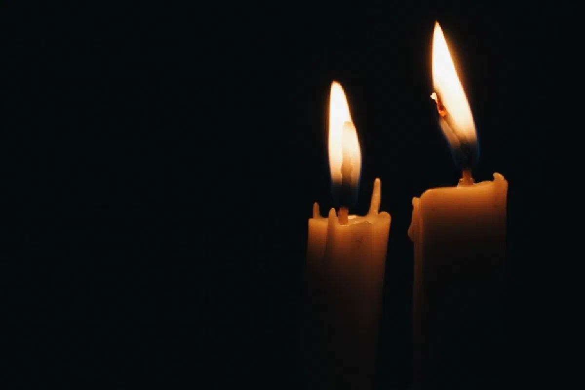 Close-up of two burning candles illuminating the dark ambiance.