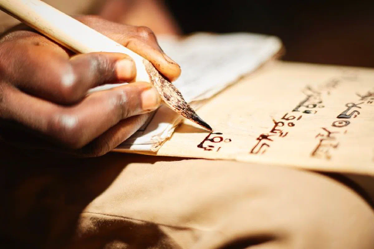 Detailed close-up of a person writing on papyrus with a traditional ink pen, highlighting cultural script.