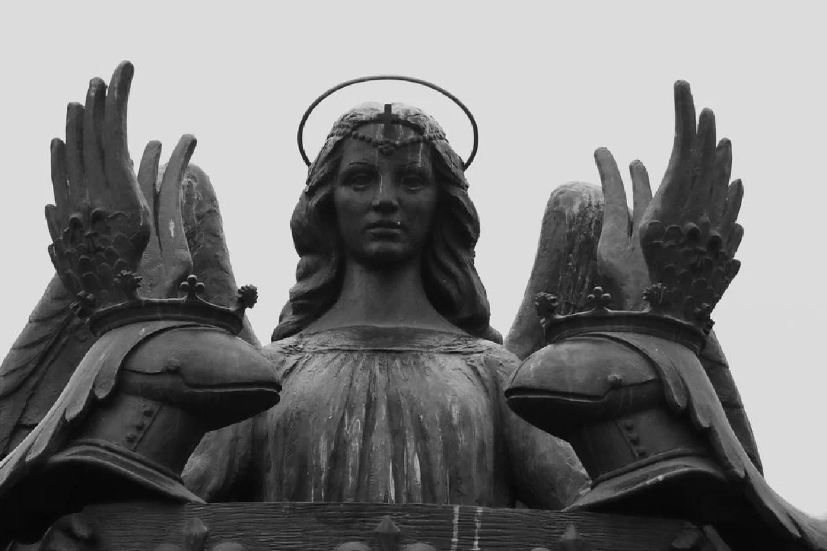 Black and white photo of a striking angel statue with a halo, evoking a sense of mysticism.