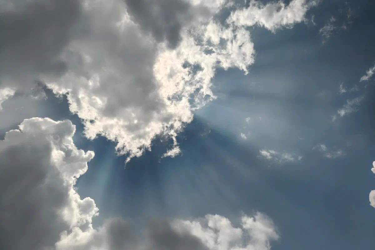 Captivating image of sun rays breaking through clouds in a vibrant blue sky.